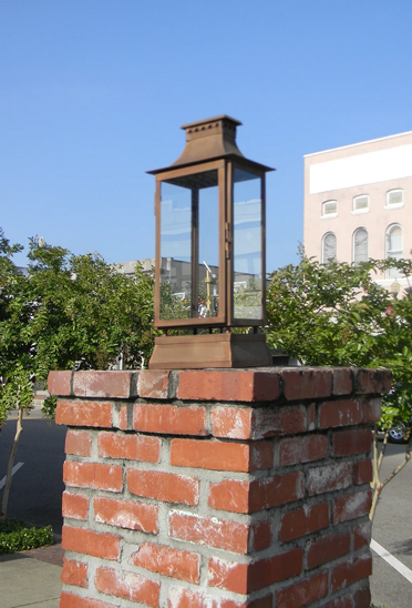 The Aspen lantern showcased as a pier mount on a brick column outside