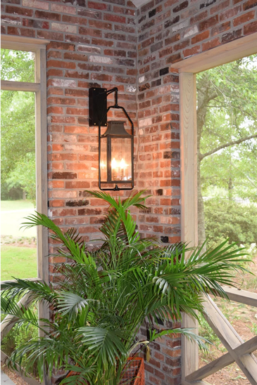 A copper Aspen lantern hung on a brick wall with a full yoke