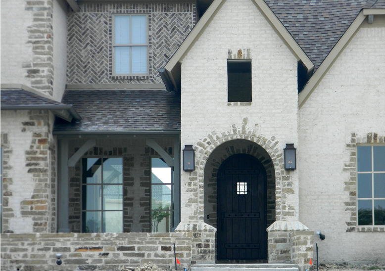 Two Aspen lanterns hung outside of the front door of a brick style house