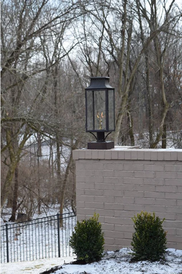 The Aspen gas powered lantern featured outside as a pier mount on top of a tan brick wall