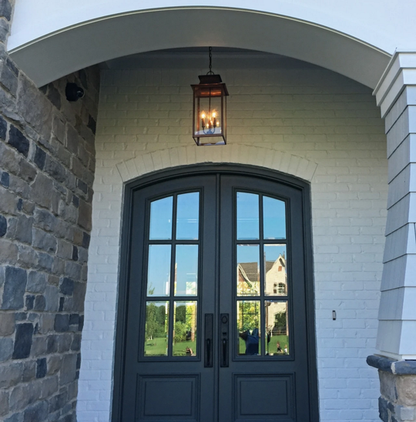 A Copper Aspen lantern hung as a pendant from a chain in front of an outside door