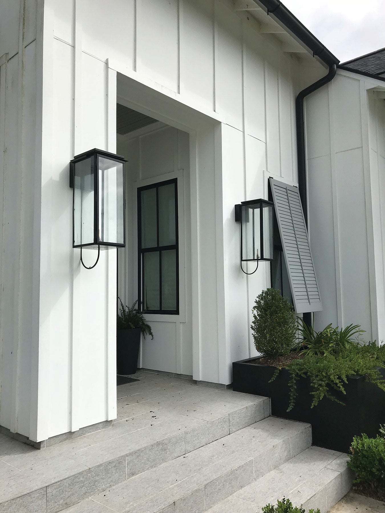 An example of the powder coat black finish on two outdoor lanterns featured next to a front door entryway